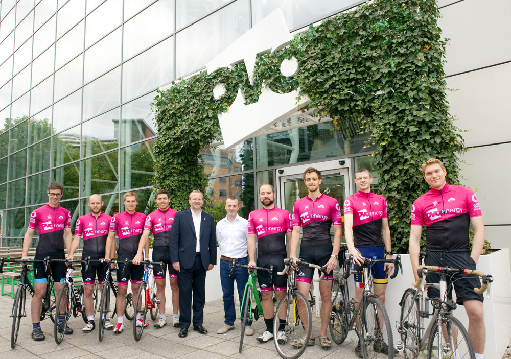 Cycle team sponsored by OVO energy with bike riders wearing pink jerseys holding racing bicycles